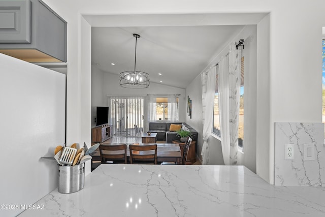 dining area with a notable chandelier and vaulted ceiling