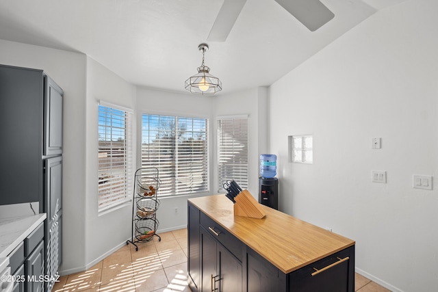 kitchen featuring light stone countertops, pendant lighting, light tile patterned floors, and a center island