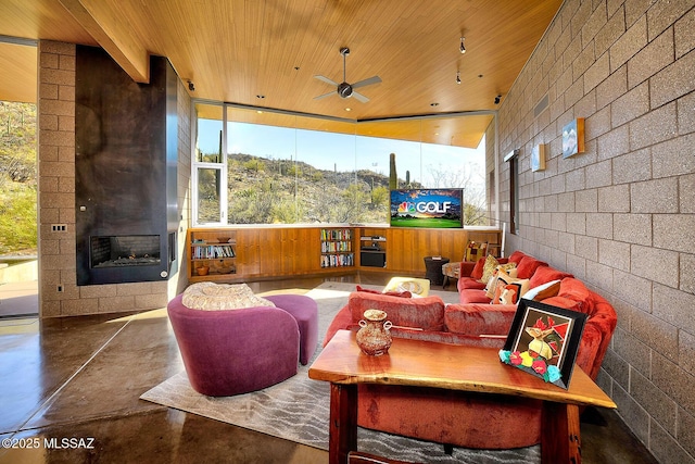 interior space featuring a ceiling fan, wood ceiling, and a multi sided fireplace