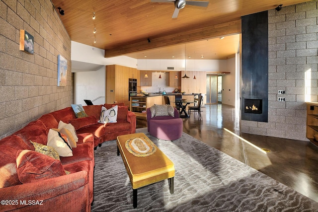 living area featuring wooden ceiling, ceiling fan, beamed ceiling, finished concrete floors, and a fireplace