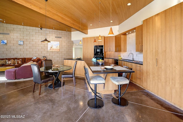 kitchen with dark countertops, pendant lighting, finished concrete flooring, and open floor plan