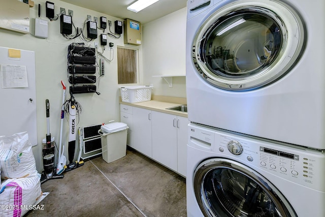 clothes washing area featuring stacked washer / dryer and cabinet space