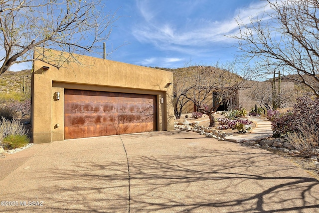 southwest-style home featuring concrete driveway, an attached garage, and stucco siding