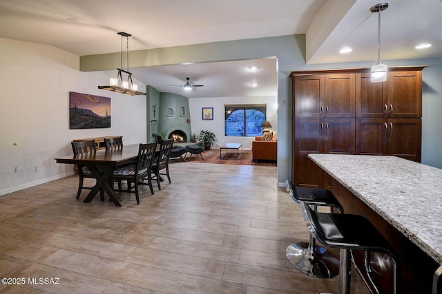 dining space featuring lofted ceiling, a large fireplace, and ceiling fan