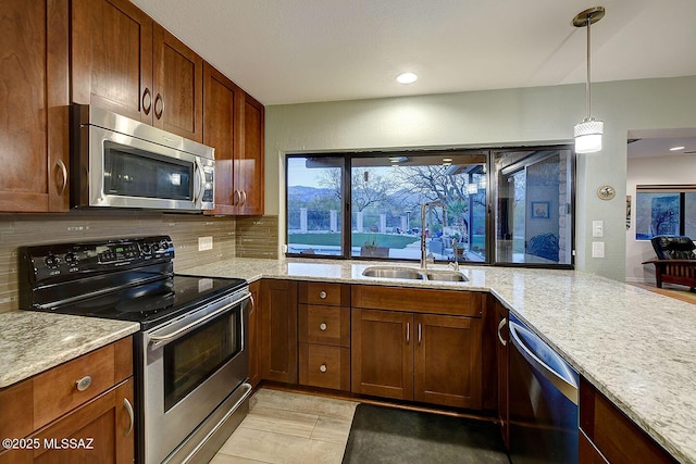 kitchen with sink, backsplash, hanging light fixtures, stainless steel appliances, and light stone countertops