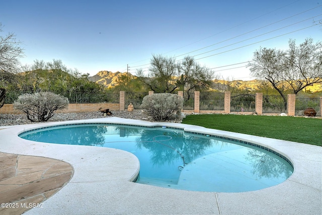 view of swimming pool featuring a mountain view and a lawn