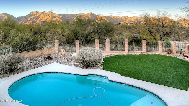 view of swimming pool with a mountain view and a yard