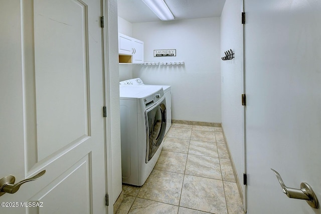 laundry room featuring washer and dryer, light tile patterned floors, and cabinets