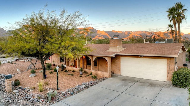 ranch-style house with a garage, a mountain view, and central AC