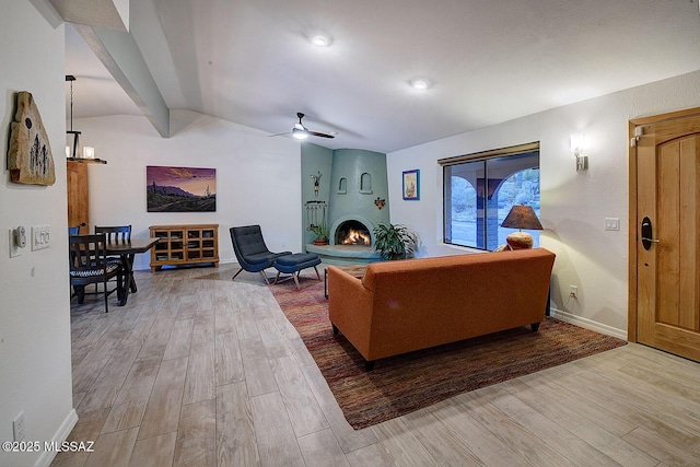 living room with beamed ceiling, a large fireplace, hardwood / wood-style floors, and ceiling fan