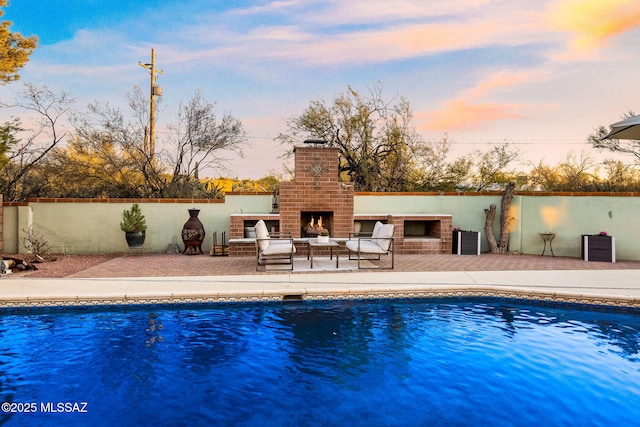 pool at dusk with central AC unit, an outdoor brick fireplace, and a patio