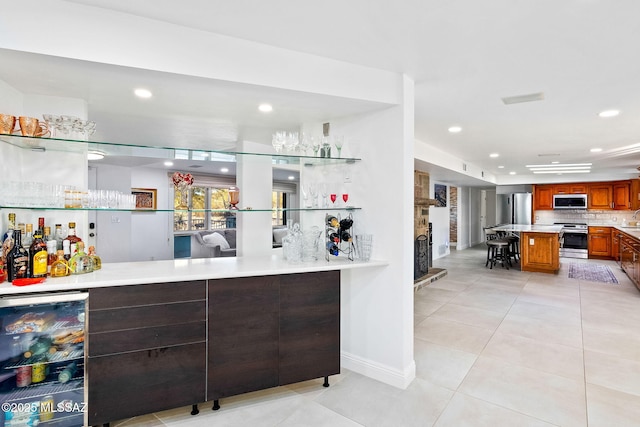 bar with beverage cooler, stainless steel appliances, tasteful backsplash, sink, and light tile patterned flooring