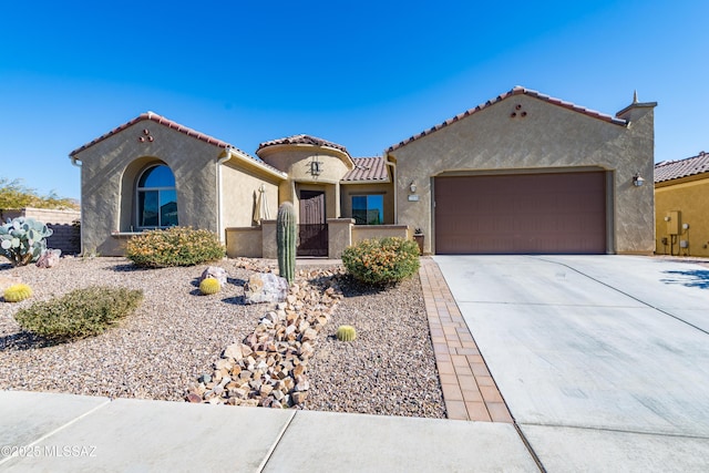 mediterranean / spanish-style house featuring driveway, a garage, a tile roof, a fenced front yard, and stucco siding