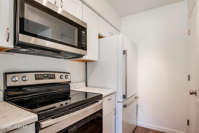 kitchen with white cabinetry, light stone counters, dark hardwood / wood-style flooring, and stainless steel appliances