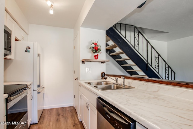 kitchen with white cabinetry, sink, stainless steel appliances, and light hardwood / wood-style floors