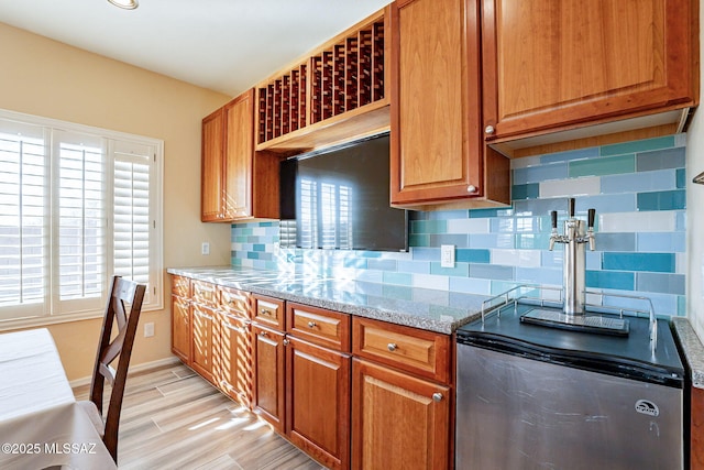 kitchen featuring light stone counters, light hardwood / wood-style floors, and backsplash