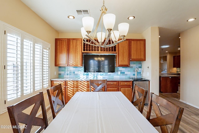 kitchen with tasteful backsplash, a chandelier, light hardwood / wood-style floors, and hanging light fixtures