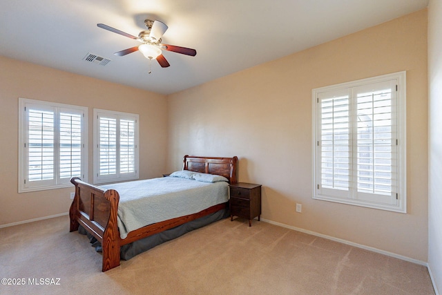 bedroom with ceiling fan, light carpet, and multiple windows