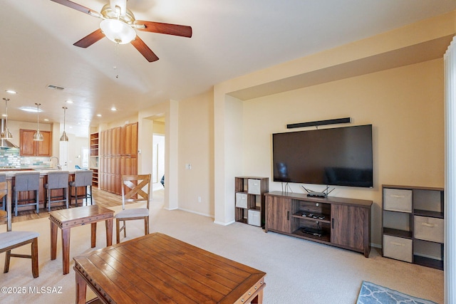 living room featuring sink, light colored carpet, and ceiling fan