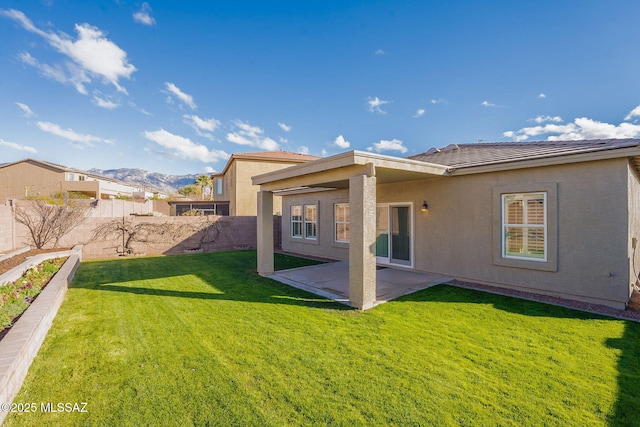 rear view of house with a mountain view, a yard, and a patio