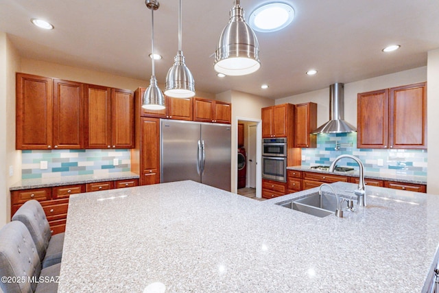 kitchen featuring appliances with stainless steel finishes, decorative light fixtures, backsplash, a kitchen breakfast bar, and wall chimney range hood