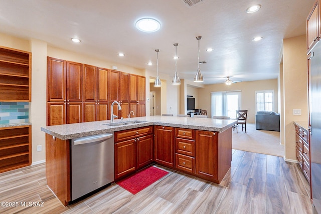 kitchen with pendant lighting, sink, a center island with sink, stainless steel dishwasher, and light wood-type flooring