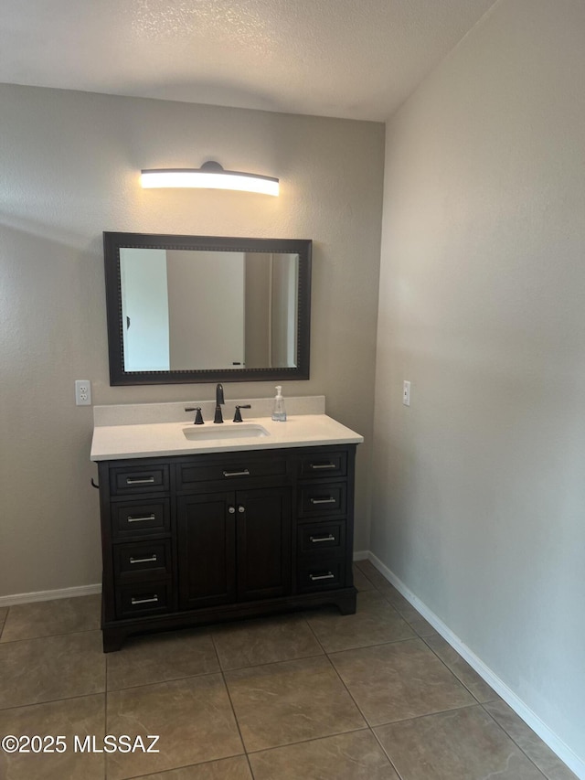 bathroom with a textured ceiling, tile patterned floors, and vanity