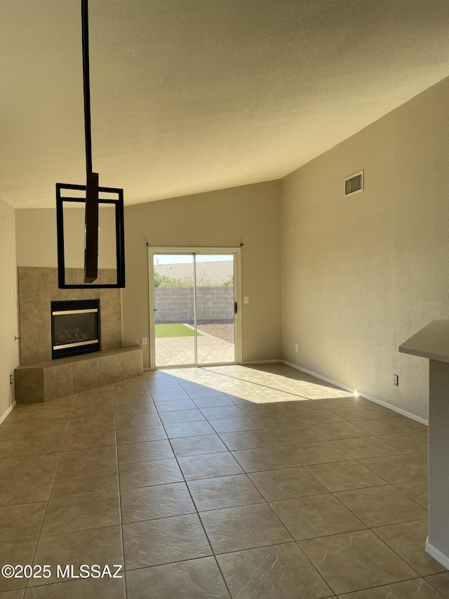 unfurnished living room with a textured ceiling, light tile patterned floors, lofted ceiling, and a fireplace