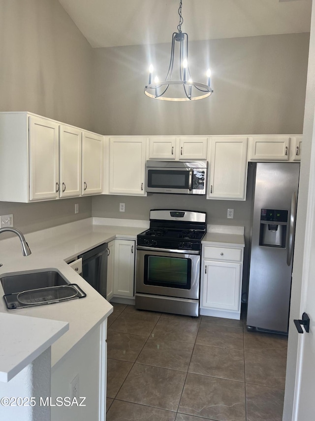 kitchen featuring white cabinetry, appliances with stainless steel finishes, sink, hanging light fixtures, and dark tile patterned floors