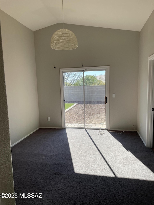 spare room with dark carpet and vaulted ceiling