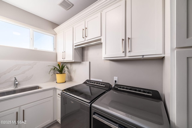 washroom with sink, cabinets, and washing machine and clothes dryer