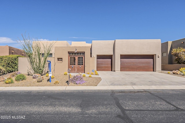 adobe home featuring stucco siding, an attached garage, and concrete driveway