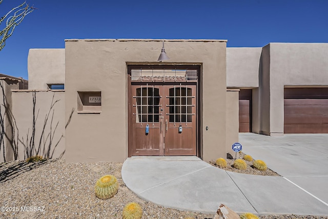 property entrance with stucco siding, french doors, and a garage