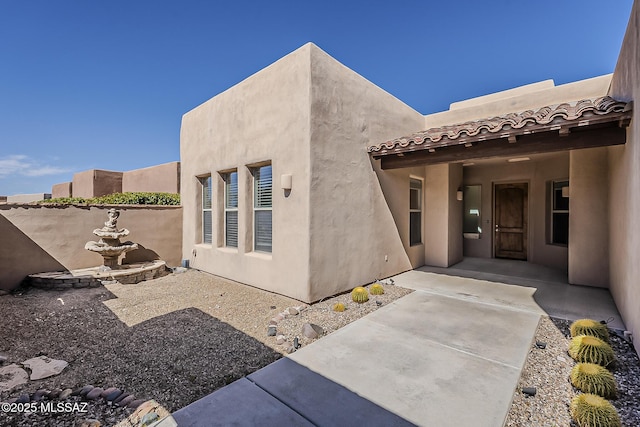 view of exterior entry featuring a tiled roof and stucco siding