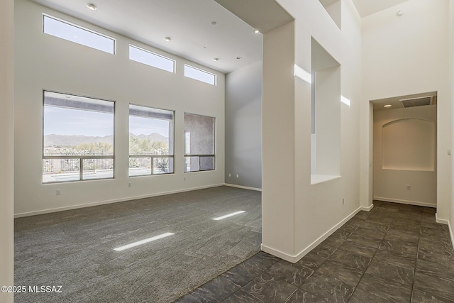 spare room featuring a mountain view, baseboards, visible vents, and a towering ceiling