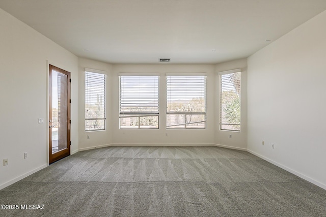 spare room featuring carpet flooring, baseboards, and visible vents