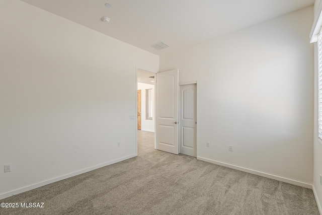 spare room with baseboards and light colored carpet