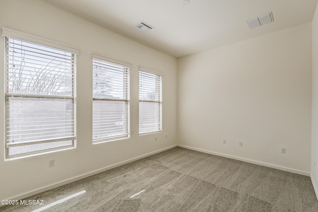 carpeted empty room featuring visible vents and baseboards