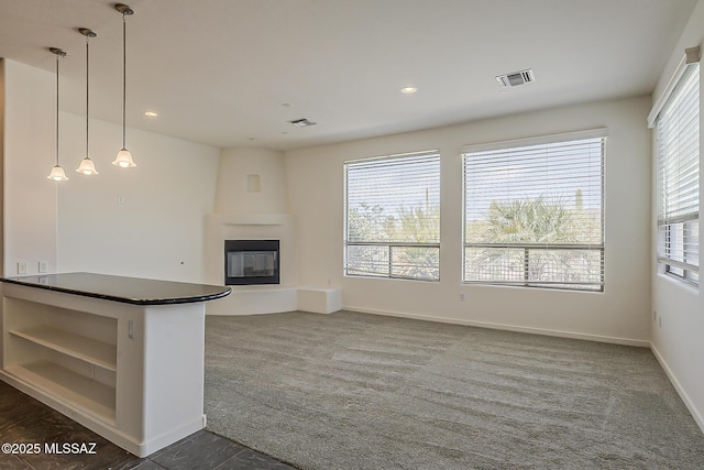 unfurnished living room featuring recessed lighting, visible vents, a large fireplace, and dark carpet