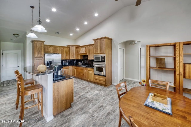 kitchen with pendant lighting, appliances with stainless steel finishes, high vaulted ceiling, tasteful backsplash, and a kitchen island