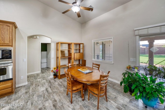 dining area with ceiling fan, high vaulted ceiling, and light wood-type flooring