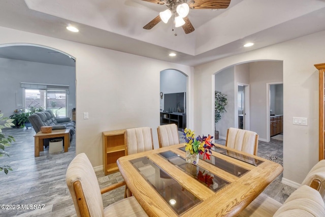 dining space featuring ceiling fan, a raised ceiling, and light hardwood / wood-style floors