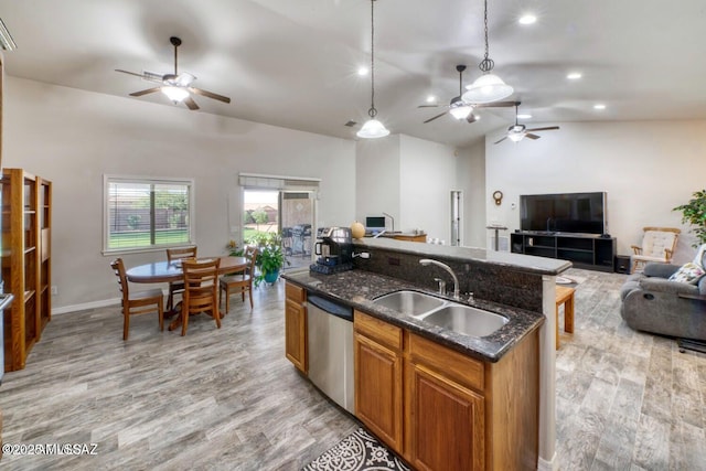 kitchen with vaulted ceiling, decorative light fixtures, sink, dark stone countertops, and stainless steel dishwasher