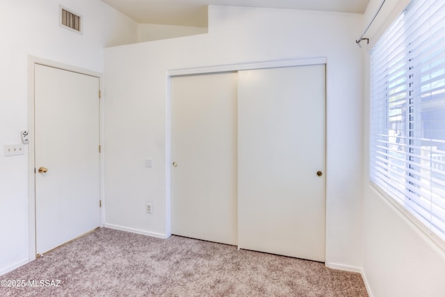 unfurnished bedroom with a closet, vaulted ceiling, and light carpet