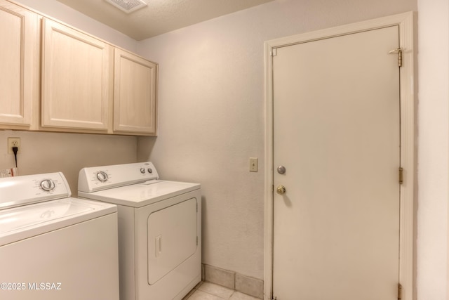 laundry area with cabinets, washing machine and dryer, and light tile patterned floors