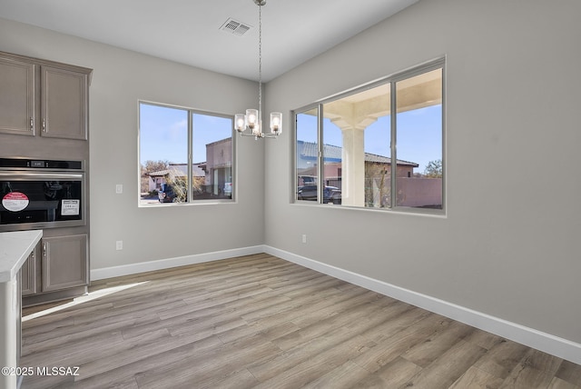 unfurnished dining area featuring a chandelier and light wood-type flooring