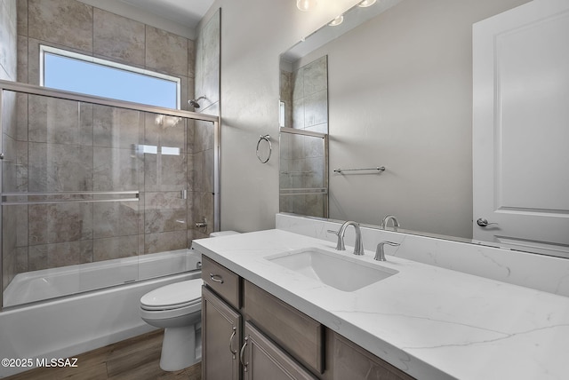 full bathroom with hardwood / wood-style flooring, toilet, shower / bath combination with glass door, and vanity