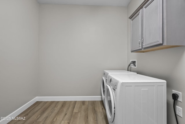 washroom featuring light hardwood / wood-style floors, cabinets, and washing machine and clothes dryer