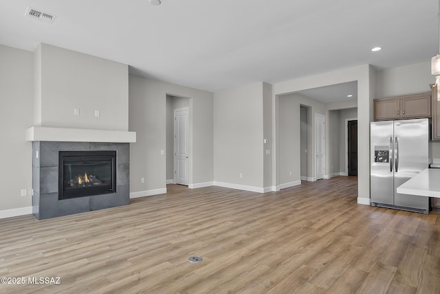 unfurnished living room with light hardwood / wood-style floors and a tiled fireplace