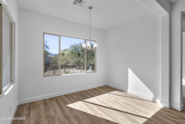 unfurnished dining area featuring wood-type flooring and an inviting chandelier